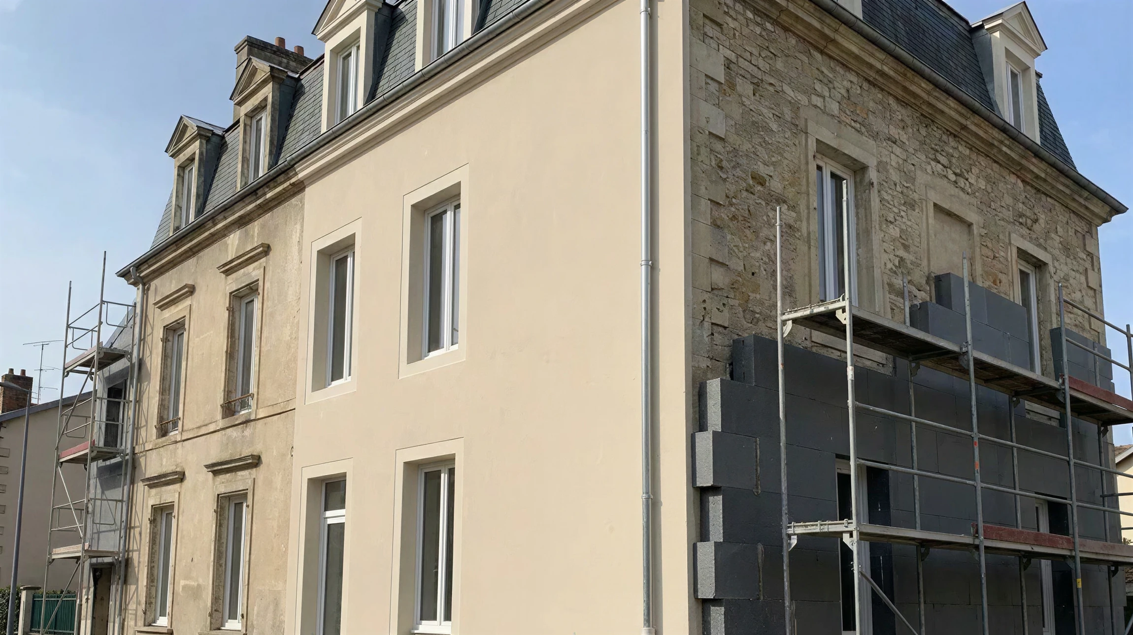 Ouvrier en vêtements de protection appliquant un enduit isolant sur façade extérieure de bâtiment en construction